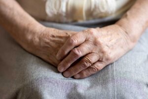 Two older adults speak calmly with a staff member in a bright assisted living common room.